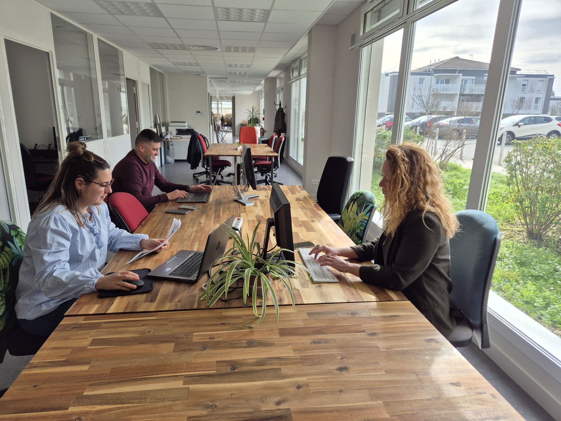Trois personnes travaillent aux bureaux de l’open-space de La Bulle, près des fenêtres